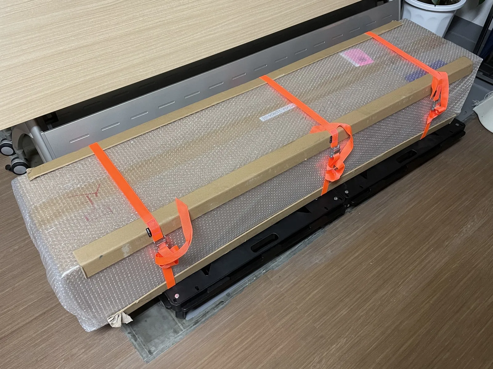 階段搬入に備えてベルトと当て材で補強したラブドールの梱包箱